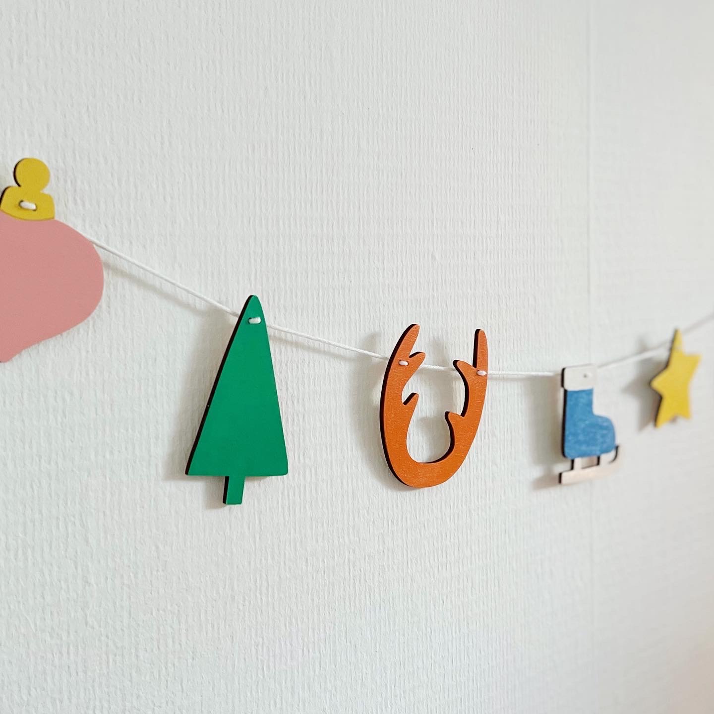 kerst slinger aan een touw tegen de muur met een kerstboom, kerstbal, gewei, ster, kerstmuts, kerst sok en een schaats