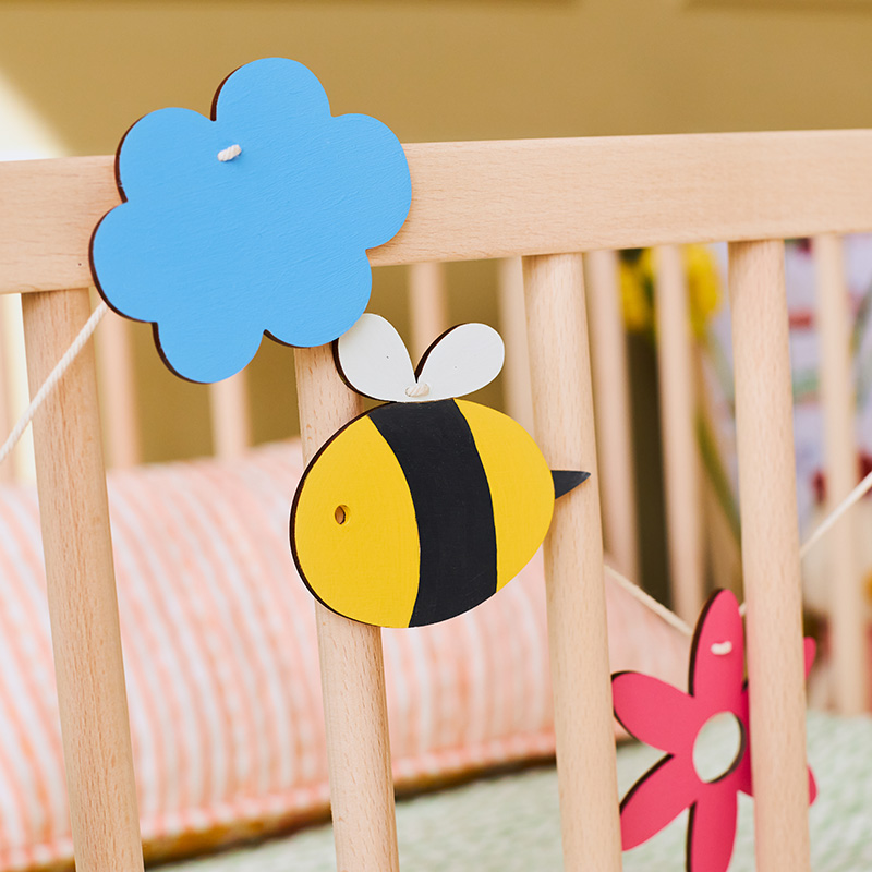 Lente houten slinger, met liefde handgeschilderd en duurzaam gemaakt. Vrolijke figuurtjes zoals bloemen en bijen, perfect voor een speelse sfeer in huis of de kinderkamer.