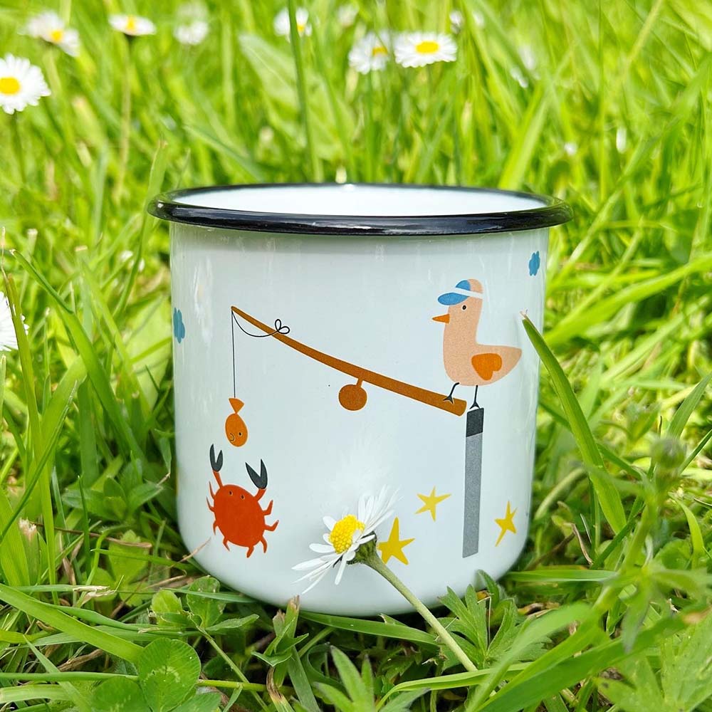 emaille mok van Kira met illustratie schelpen en krab op strand en meeuw met hengel