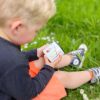 Een jongetje houdt een emaille mok vast zittend in het gras