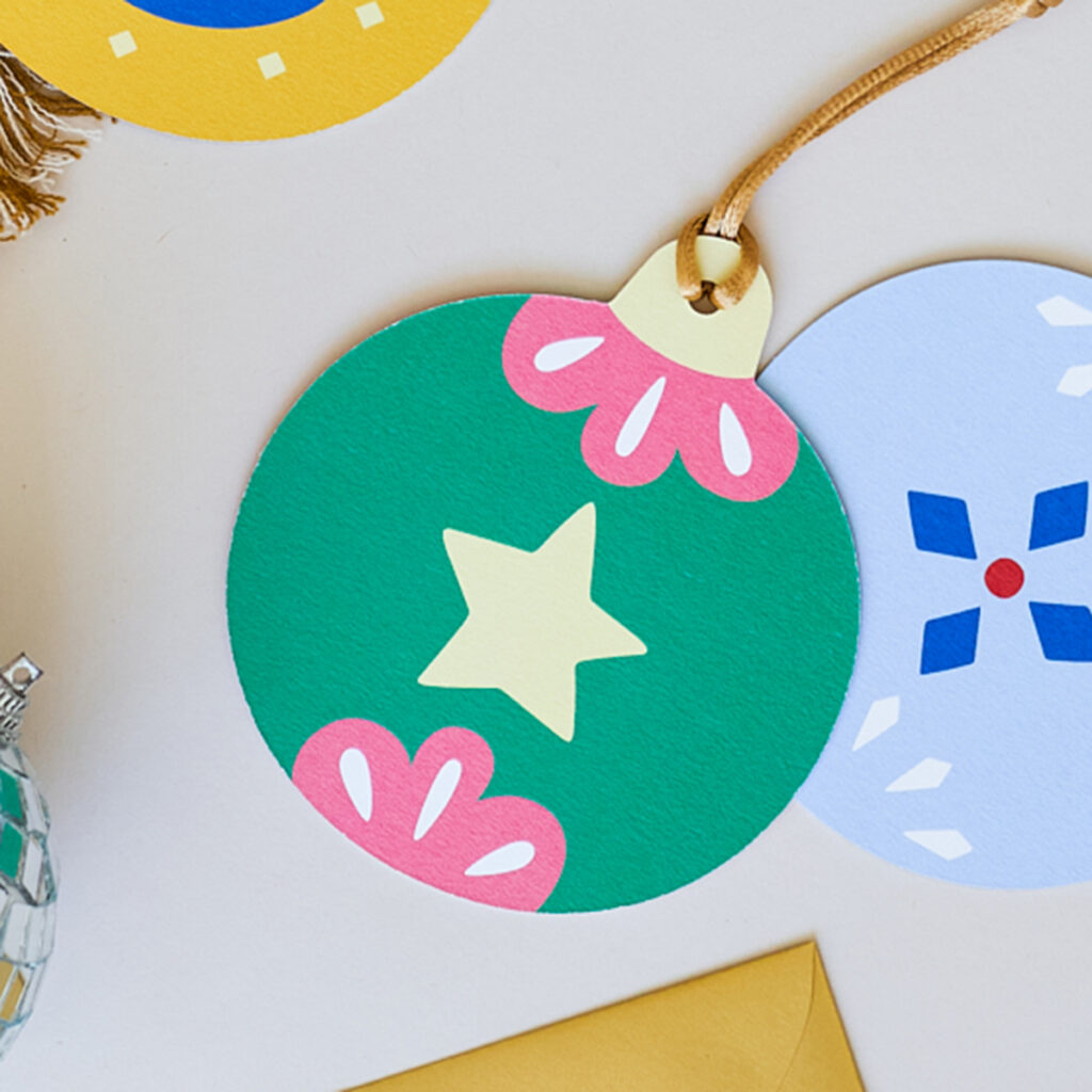 Stevige papieren kerstbal met een heldere en vrolijke illustratie van een ster. Gemaakt van duurzaam materiaal, ideaal voor een milieuvriendelijke kerstversiering. De kerstbal heeft een levendige uitstraling, perfect voor in de kerstboom of als kleurrijke decoratie.